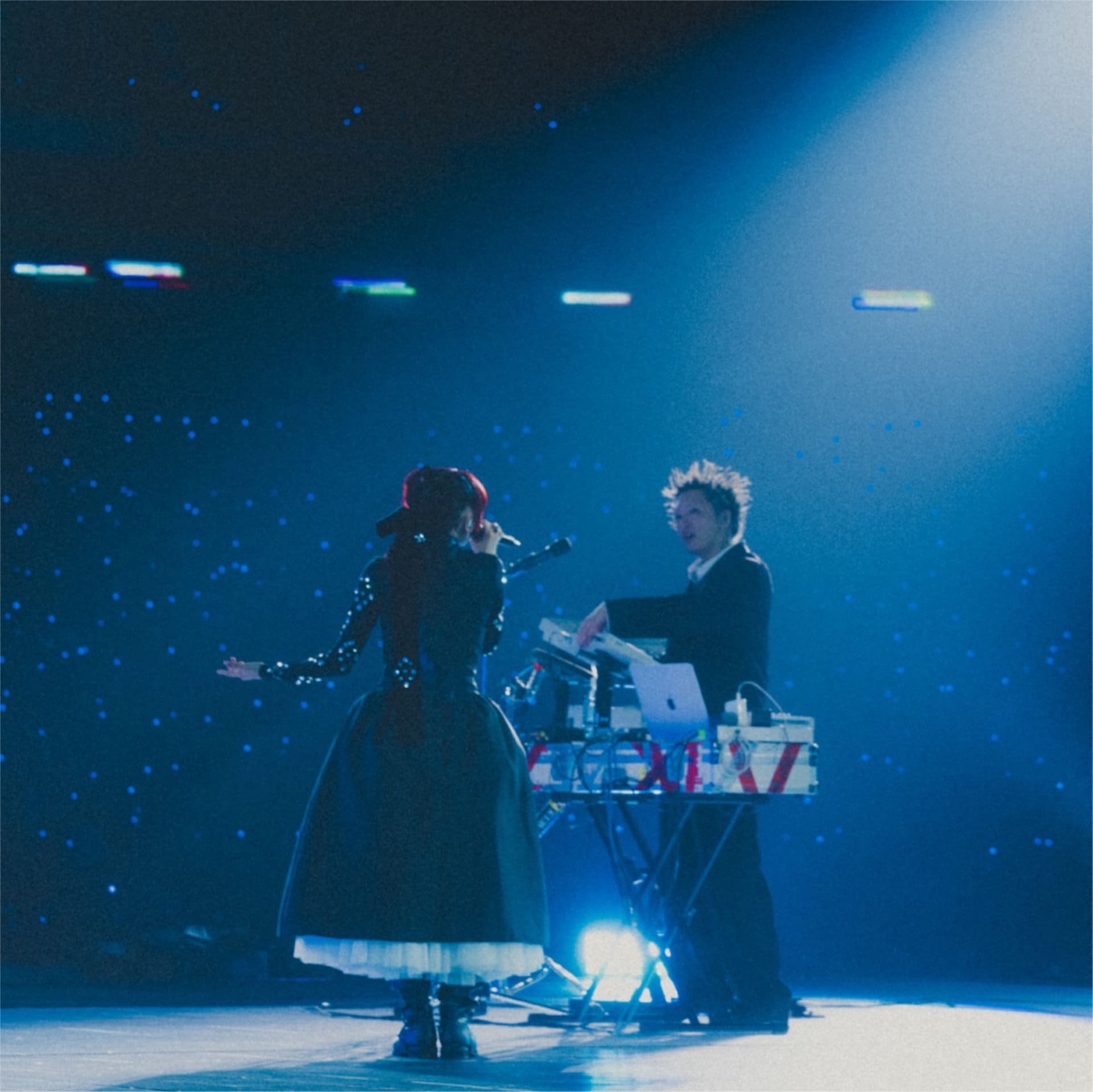 Capa do álbum ao vivo do YOASOBI com Ayase e ikura no palco sob luzes azuis