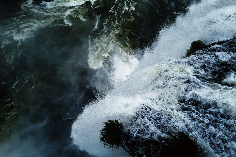 Fotografia de água corrente e espuma sobre rochas, parte da exposição de Nanase Aikawa