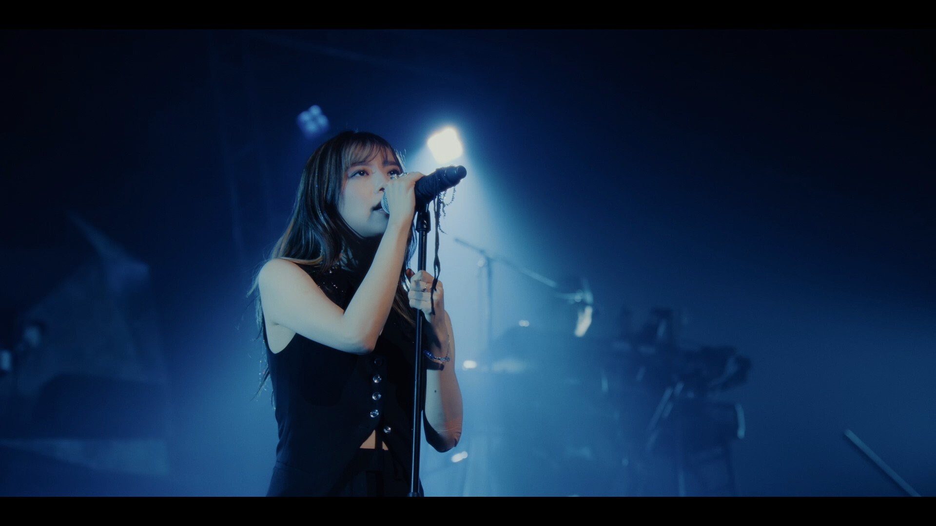 milet canta ao microfone durante apresentação usada no clipe de My Voice, My Life